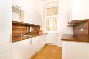 A compact kitchen with white cabinets, a wooden countertop, a window, and a built-in oven.