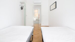 Ein schmaler Korridor mit je zwei Betten an den Seiten, der zu einem Badezimmer mit Fenster führt.