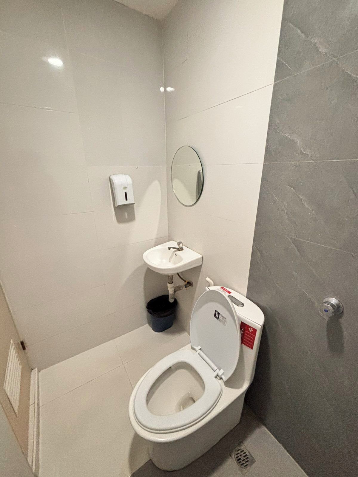 Un baño moderno con inodoro, lavamanos y espejo.