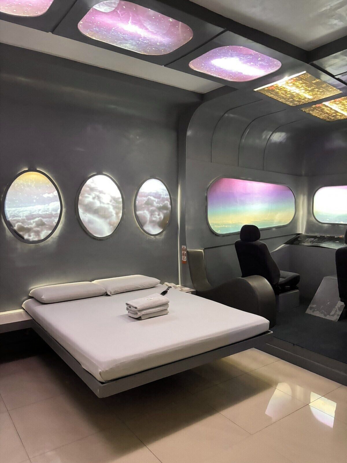 Cabina de avión moderna con cama, una mesita y una ventana con vistas a las nubes.