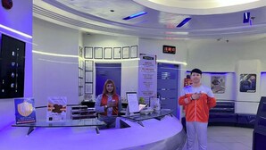 A reception desk with a digital clock, framed documents on the wall, and a notice about the establishment being a drug-free workplace. - Astrotel Cubao (Quezon City)