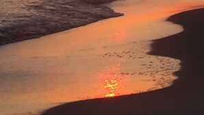 Un atardecer sobre un mar tranquilo con olas suaves.