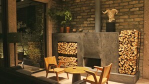 A cozy indoor seating area with a fireplace, wooden furniture, and a stone wall. - Xun Sun Hotel (Hangzhou)