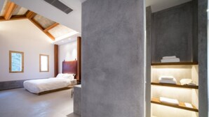 A modern bedroom with a large bed, a wooden ceiling, and a built-in shelf with towels. - Xun Sun Hotel (Hangzhou)