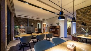 A modern interior with a brick wall, wooden tables, and blue chairs. - Xun Sun Hotel (Hangzhou)