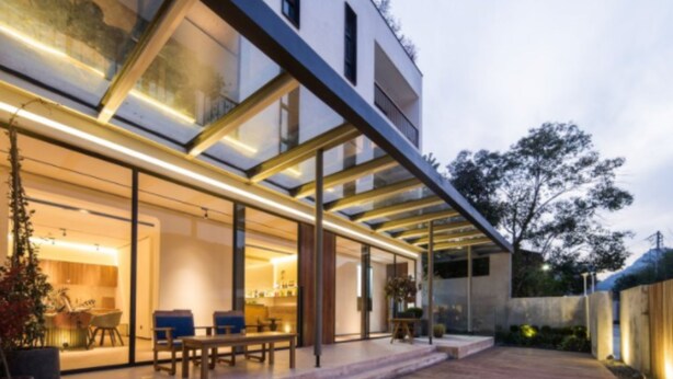 A modern building with a glass facade, outdoor seating area, and a well-lit interior. - Xun Sun Hotel (Hangzhou)
