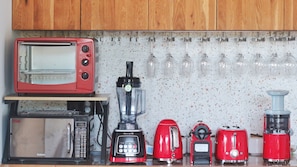 A kitchen with a red toaster, a blender, a red kettle, a red toaster, and a red blender.