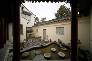 A traditional courtyard with a stone pool, potted plants, and a tiled walkway. - Lianyungang Donghai Shisu Onsen Villa (Lianyungang)