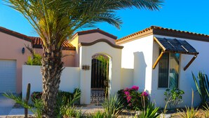 Una casa con fachada blanca, techo marrón y un panel solar.