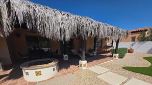 Un patio con techo de paja, mobiliario exterior y un jacuzzi.