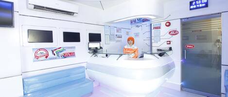 A modern reception area with a digital clock, glass partitions, and a blue seating area.