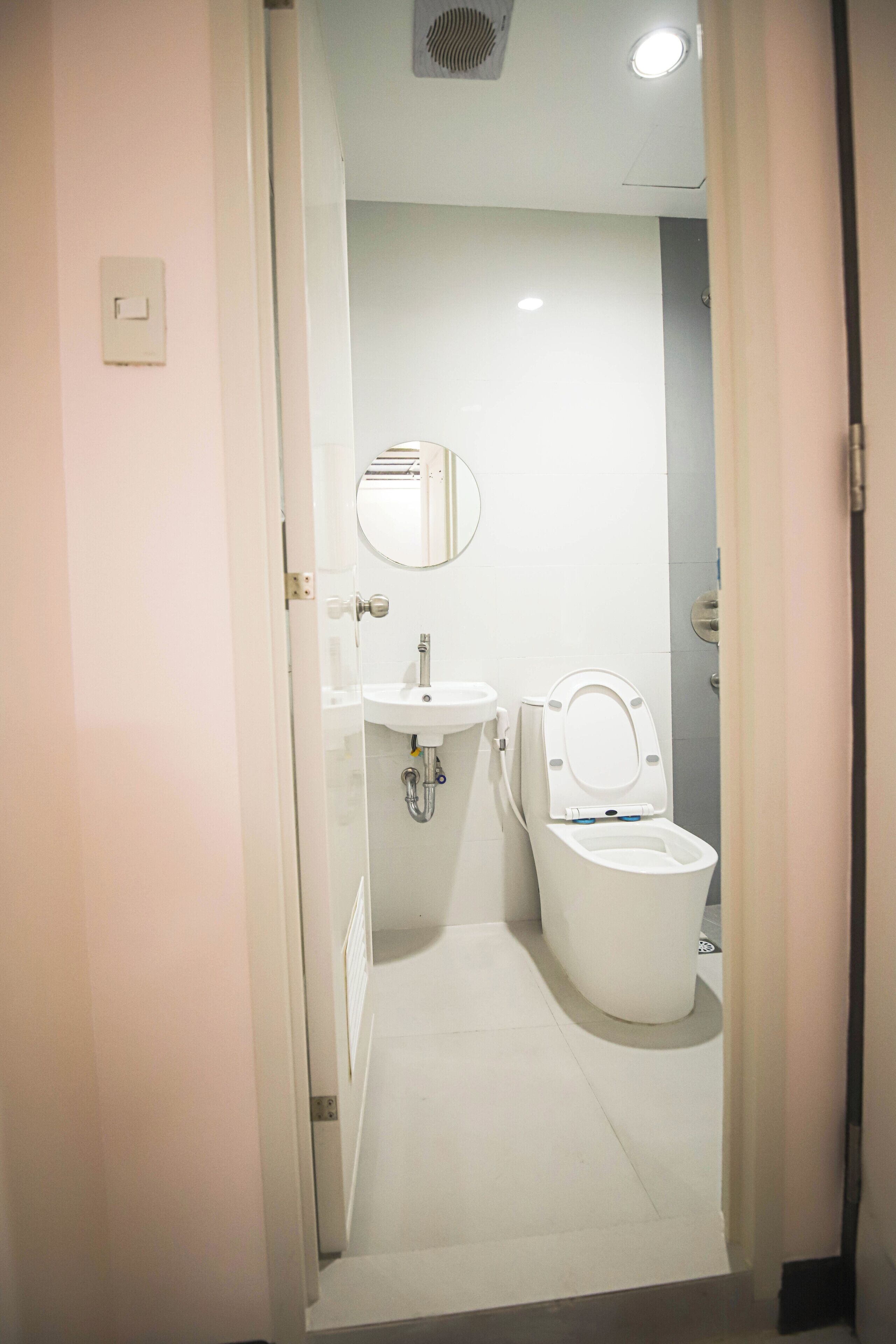 Un baño moderno con inodoro, lavamanos y espejo.