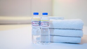 Dos botellas de agua Astrotel y una pila de toallas blancas sobre una superficie blanca.