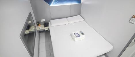 A modern hotel room with a bed, a nightstand, a mirror, and a wall mural of Earth from space.