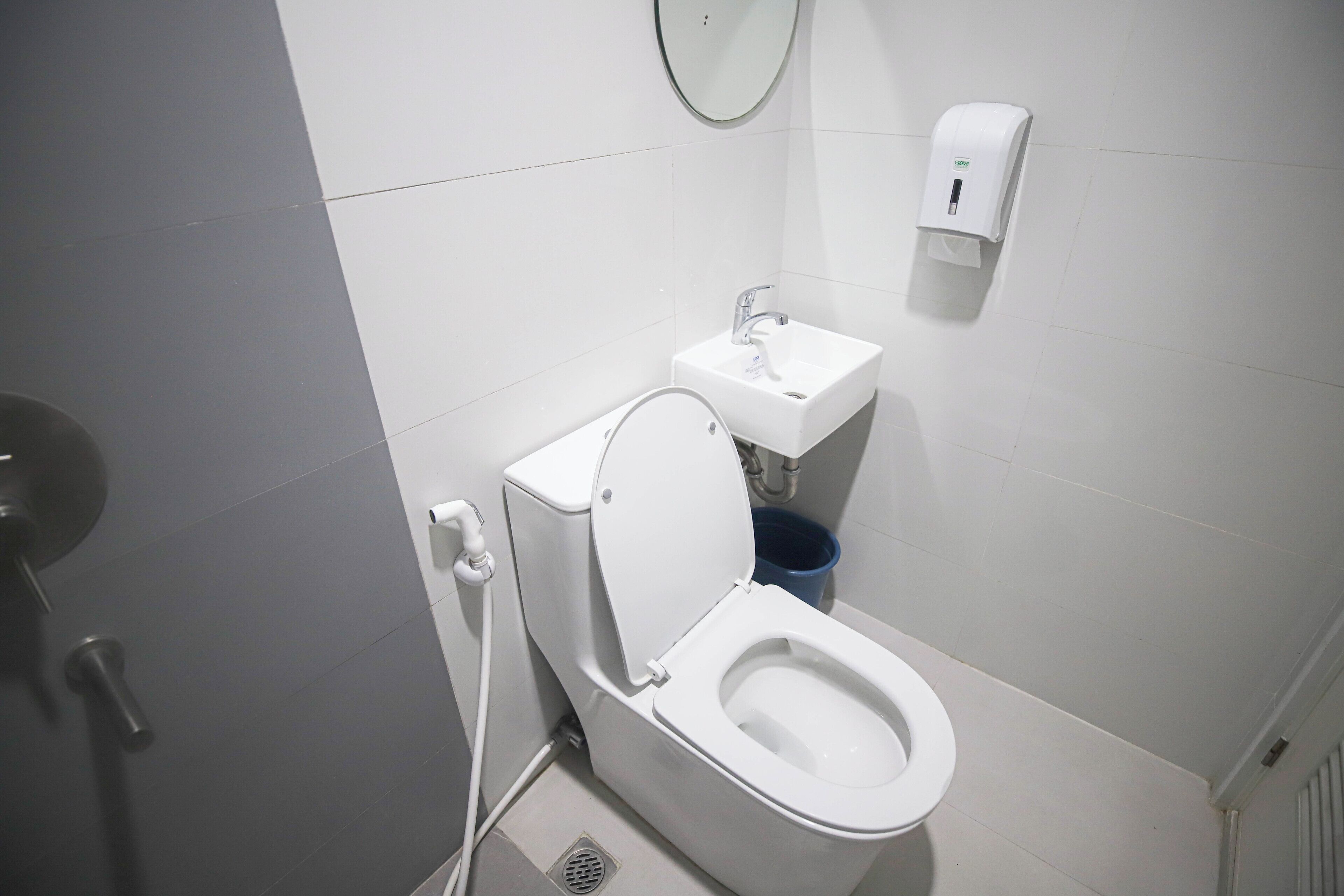 Une salle de bain moderne équipée de toilettes, d’un lavabo et d’un sèche-mains.