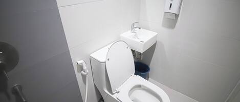 Une salle de bain moderne équipée de toilettes, d’un lavabo et d’un sèche-mains.