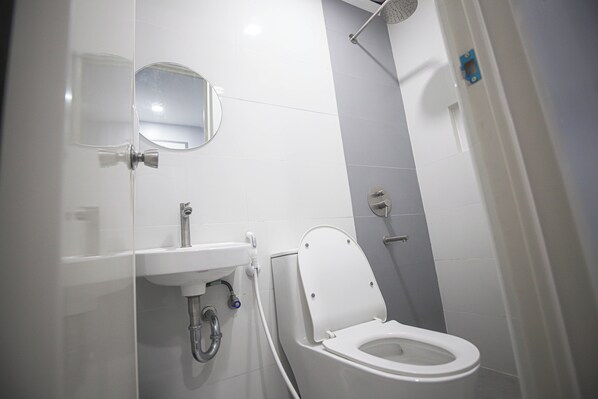 A modern bathroom with a toilet, sink, and shower. - Astrotel Calamba (Calamba)