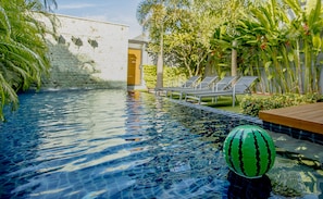 A swimming pool with clear water, lounge chairs, and tropical plants. - Almali Villa Mali (Rawai)