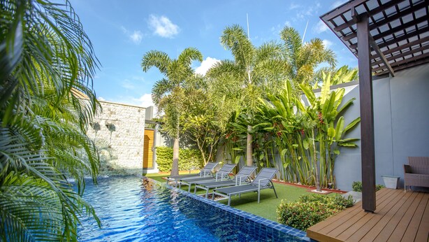 Ein Swimmingpool mit Liegestühlen, umgeben von tropischer Bepflanzung und einer Pergola.