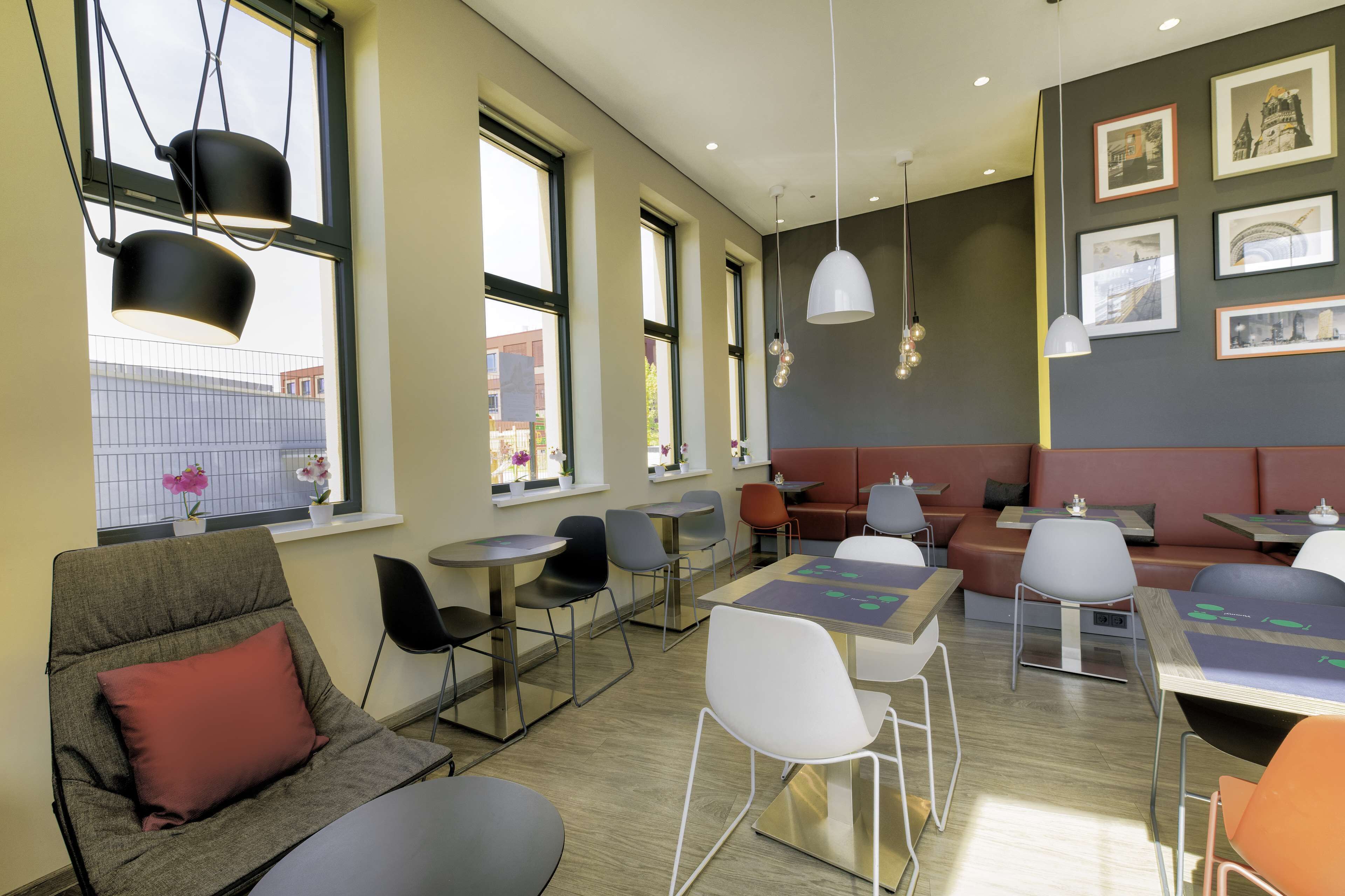A modern cafe with seating arrangements, tables, and pendant lighting.