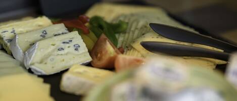 A variety of cheeses and fruits on a platter.