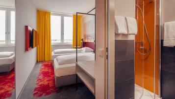 Una habitación de hotel con cama, ducha y vistas a la ciudad.