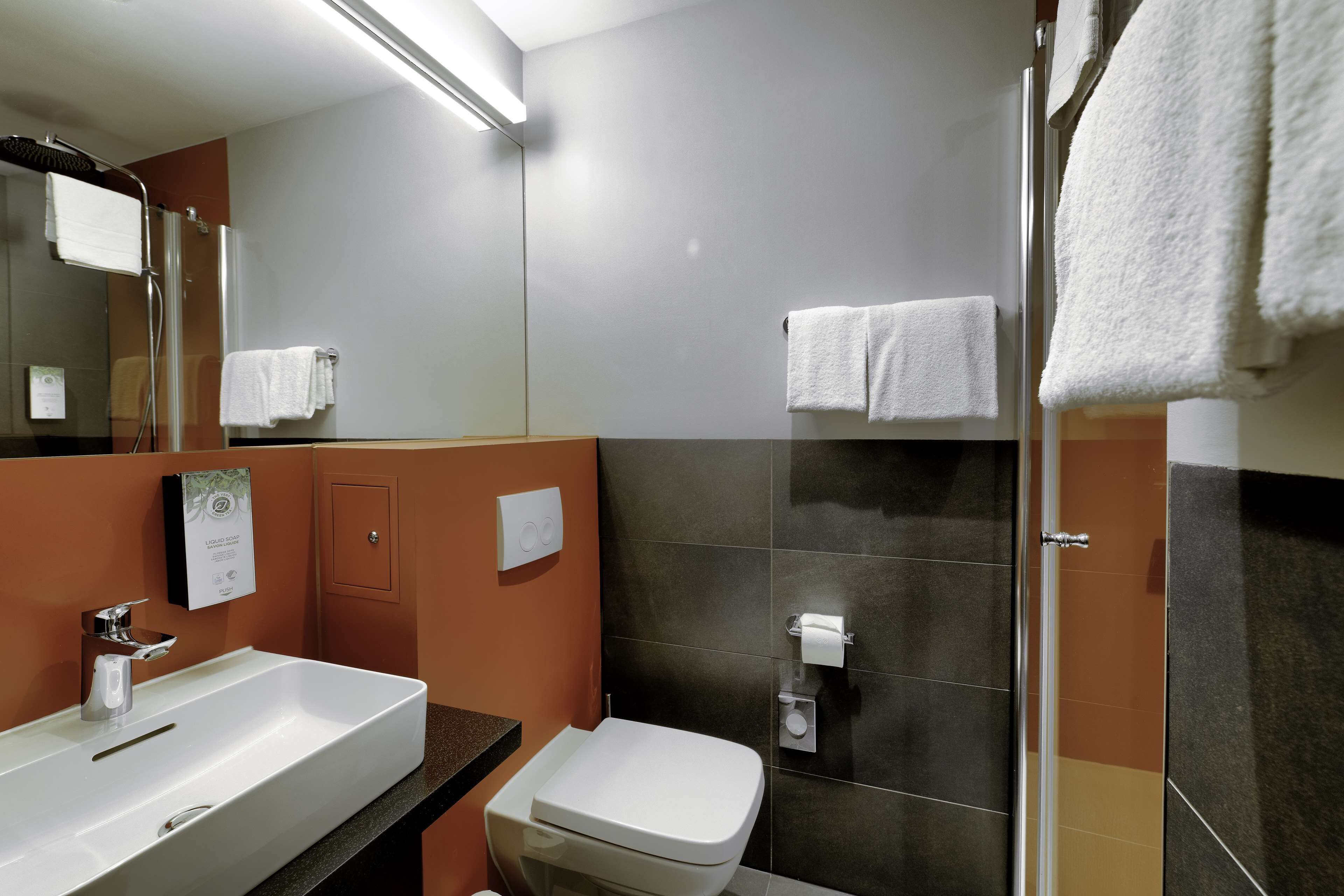 A modern bathroom with a large sink, toilet, and shower.