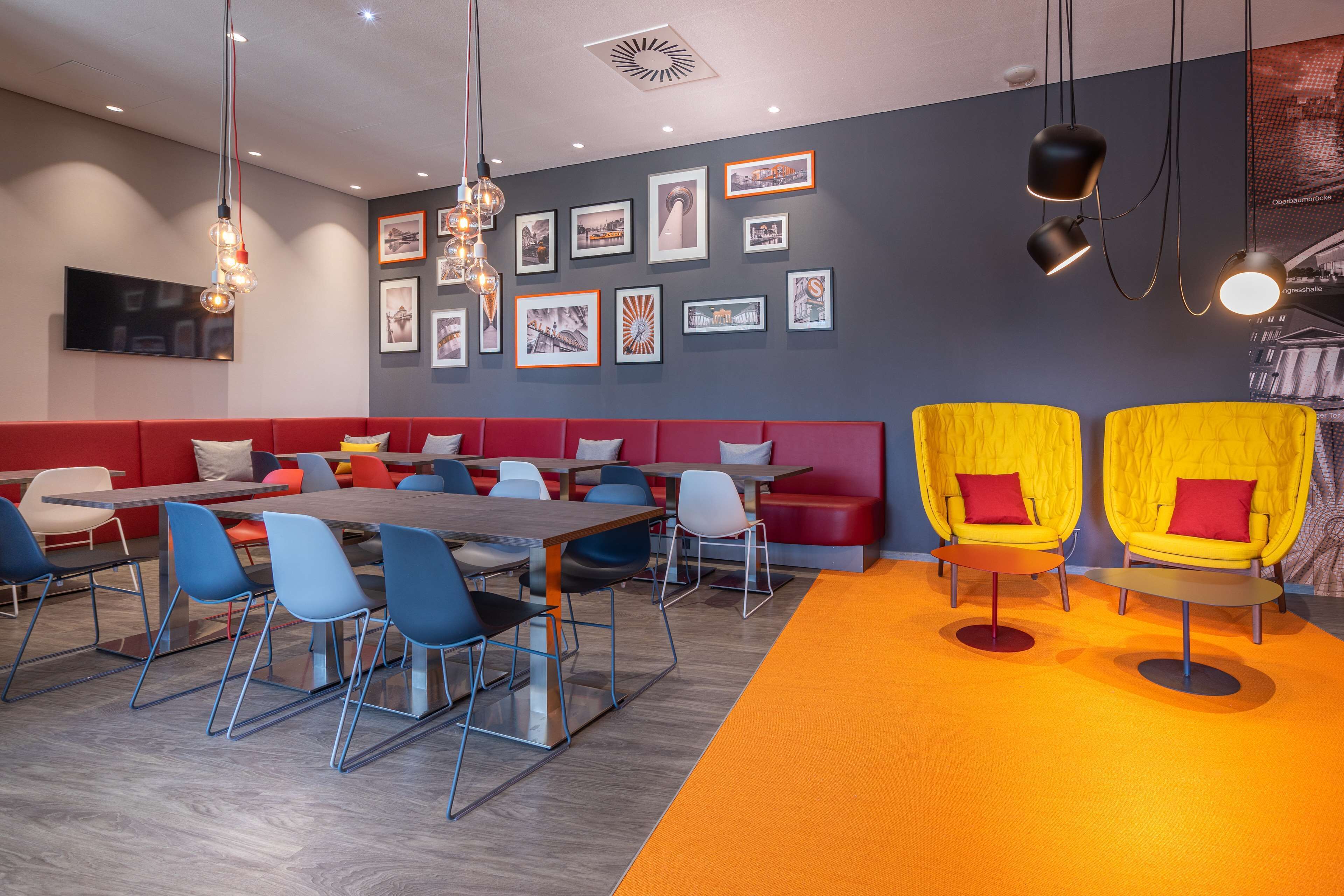 Un comedor moderno con una mesa larga, sillas azules, asientos rojos y sillones amarillos.