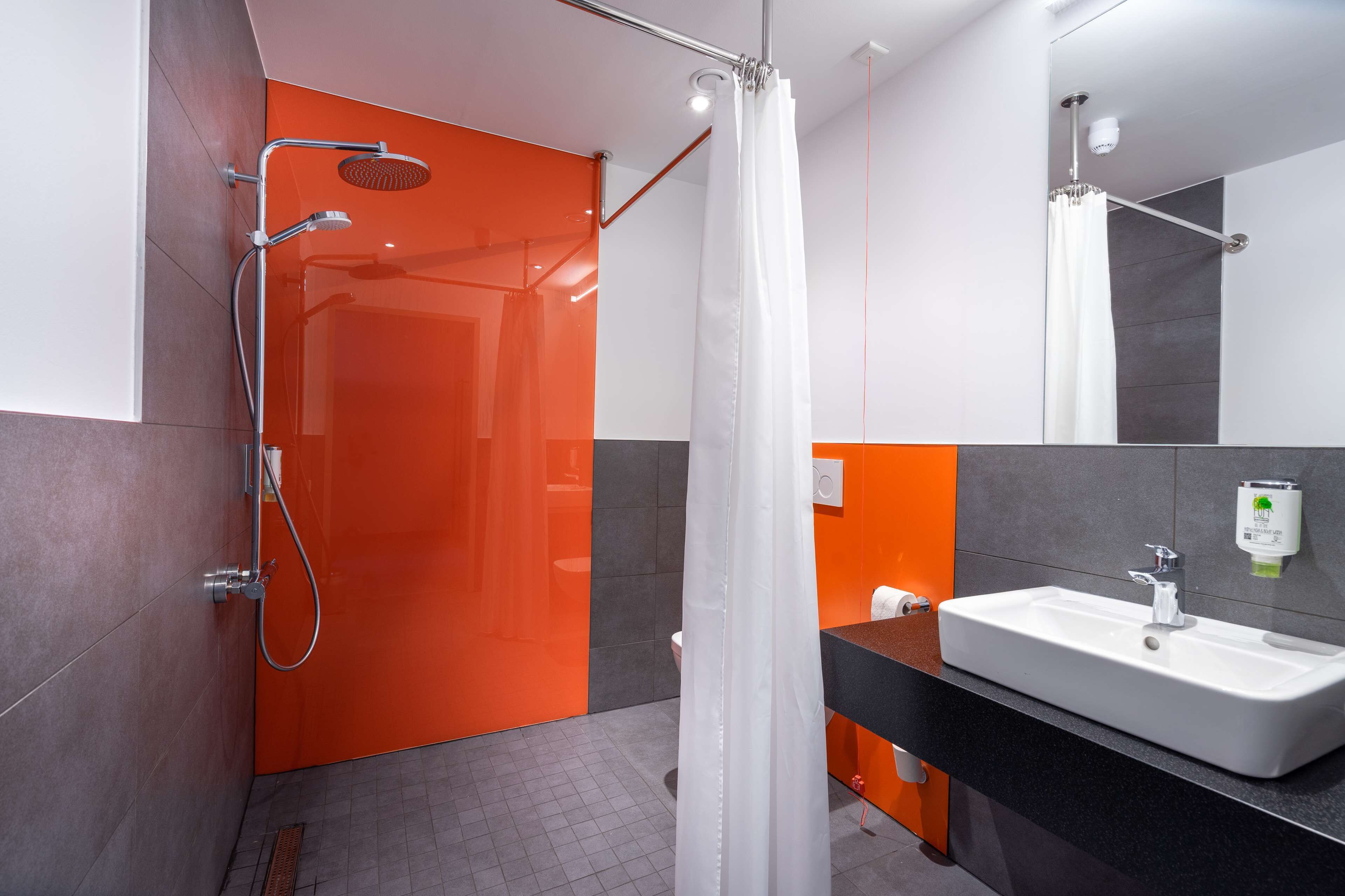 Un baño moderno con ducha, lavamanos y espejo.
