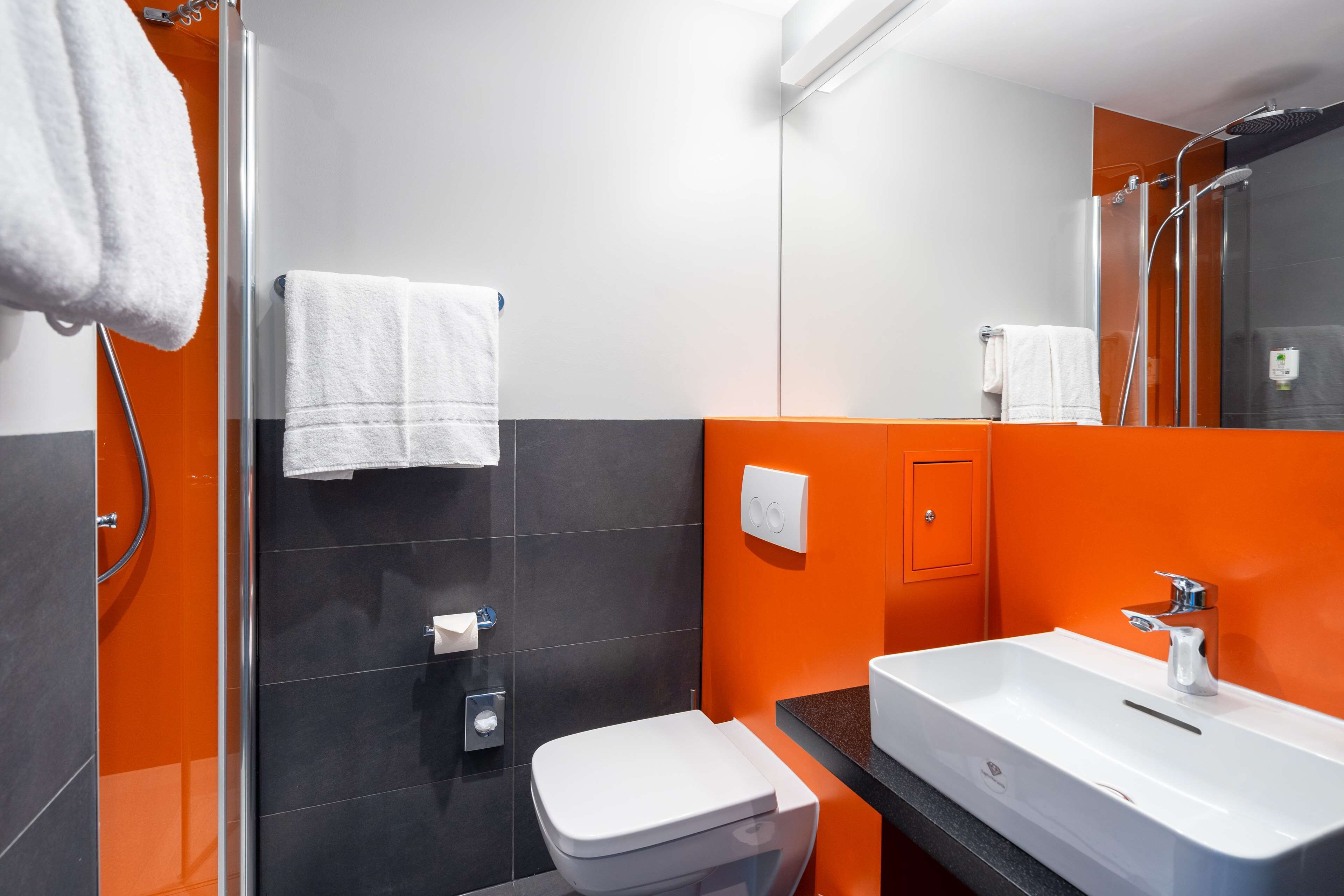 A modern bathroom with a white toilet, a sink, and a shower.