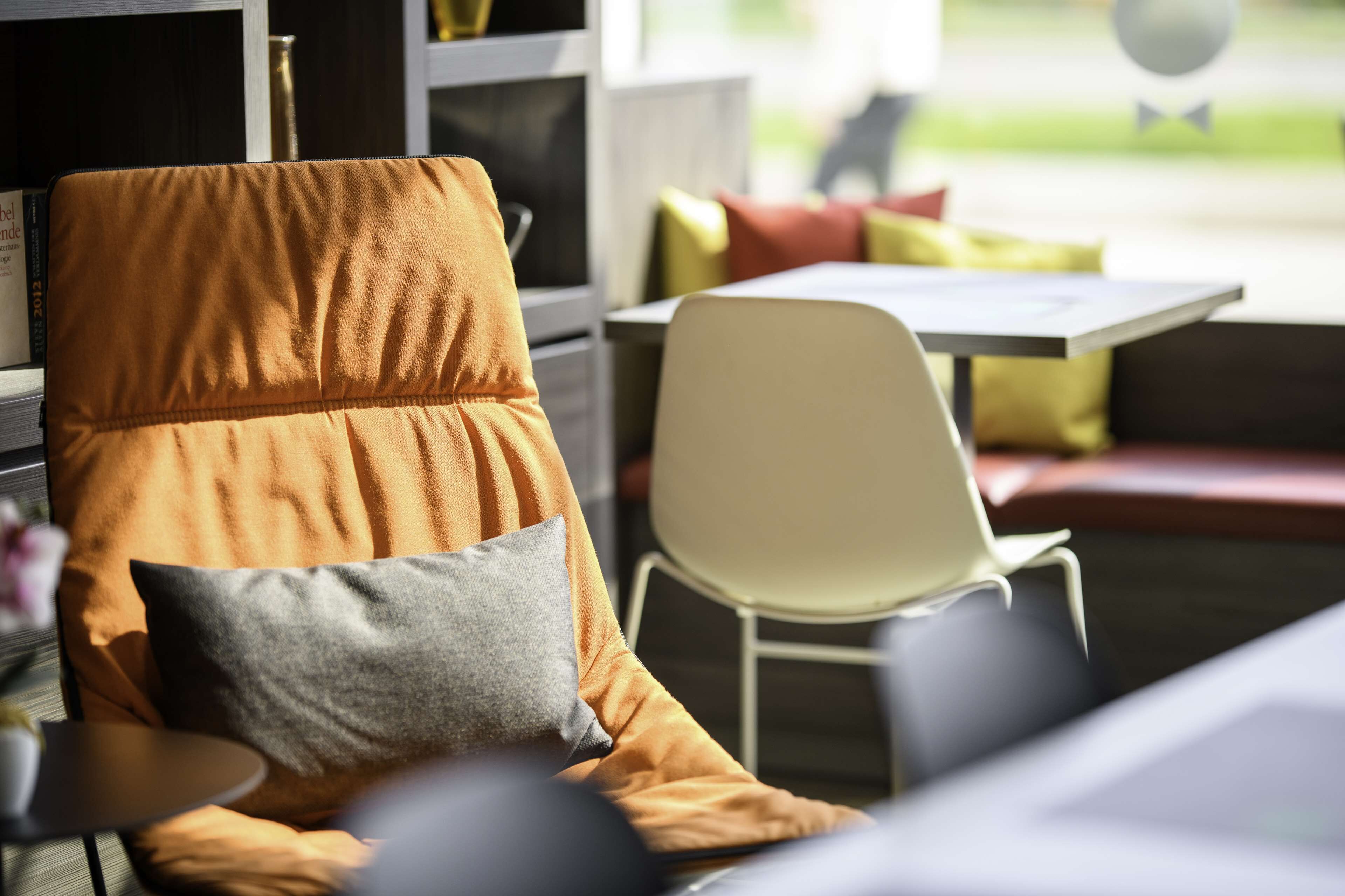 Een moderne zithoek met een comfortabele oranje fauteuil, een witte stoel en een bijzettafeltje.