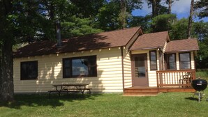 A log cabin with a porch, a picnic table, and a grill. - Pet-Friendly Cabin On The Lake With Fireplace (St. Germain)