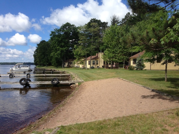 A lakeside property with a dock, a sandy area, and cabins.