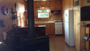 A cozy cabin interior with a wood stove, kitchen area, and a living room with a fireplace. - Pet-Friendly Cabin On The Lake With Fireplace (St. Germain)