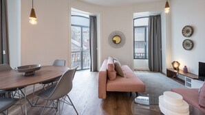 Een moderne woonkamer met een ronde eettafel, een roze bank en een tv-meubel.
