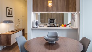 Een moderne keuken met houten kastjes, een magnetron, een waterkoker en een fruitschaal op het aanrecht.