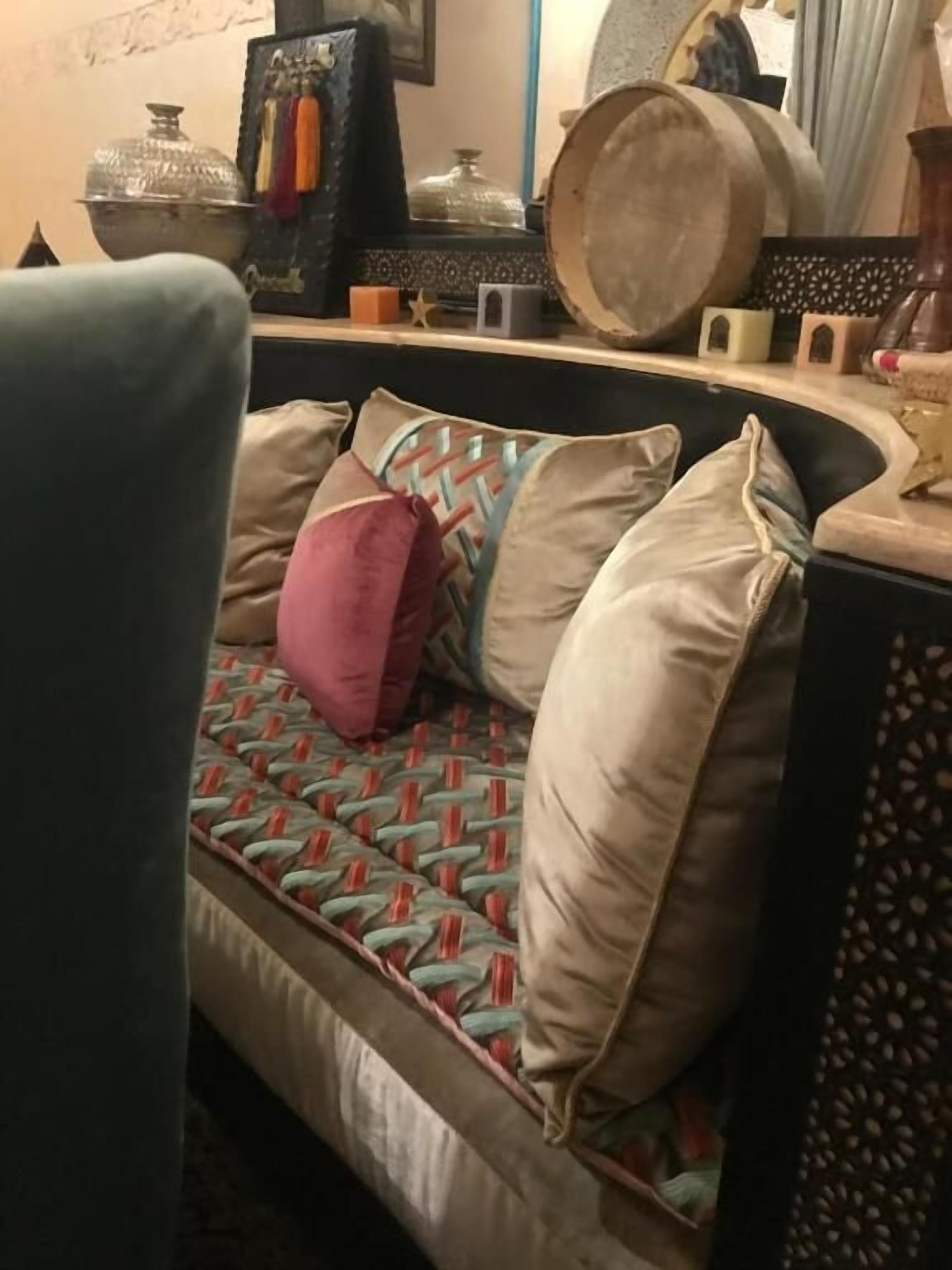A sofa with patterned cushions and a decorative wall behind it.