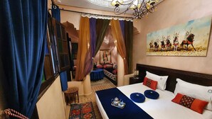 A hotel room with a large bed, a patterned rug, and a painting on the wall. - Riad La Porte Du Bouregreg (Salé)