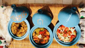 Three blue ceramic dishes with lids, each containing different food items, placed on a woven mat.