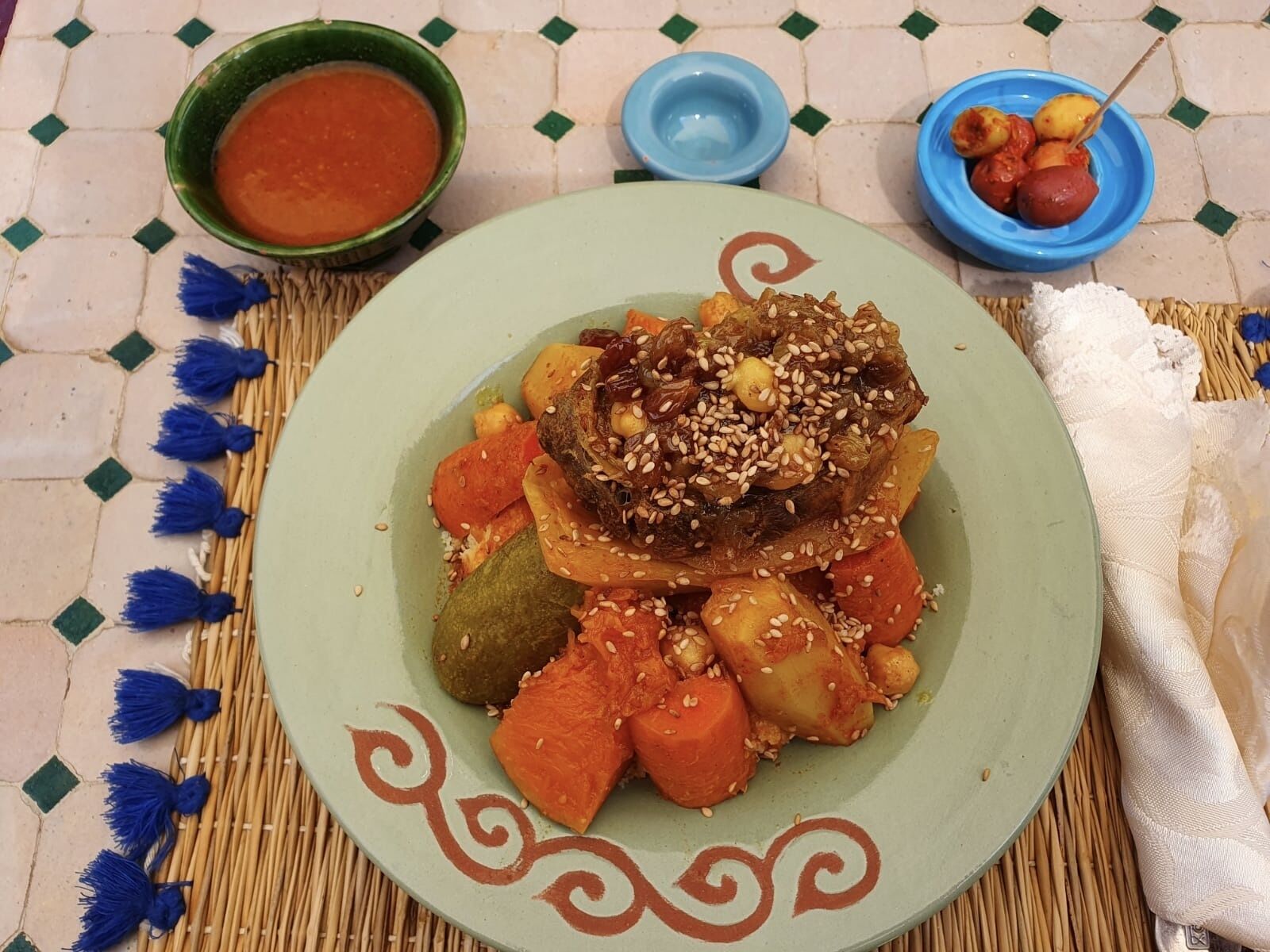 Un plato de comida con un plato decorativo, un bol de salsa y un bol azul con comida.