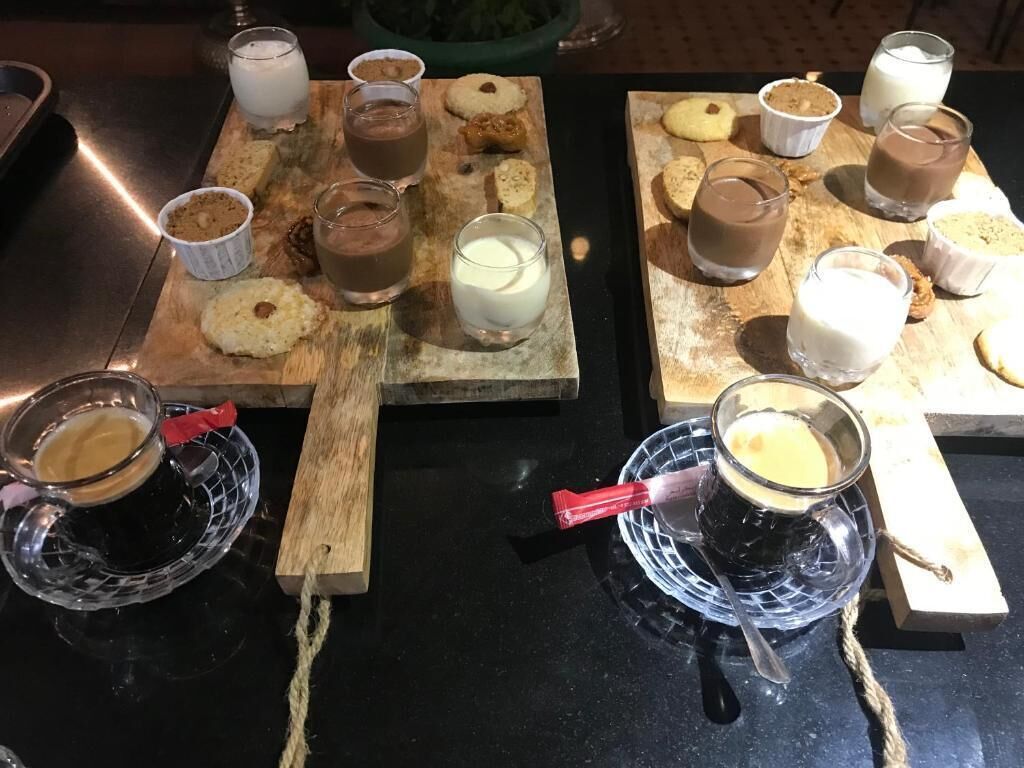 Una mesa con distintos alimentos y bebidas, como galletas, pasteles y refrescos en vasos y tazas.