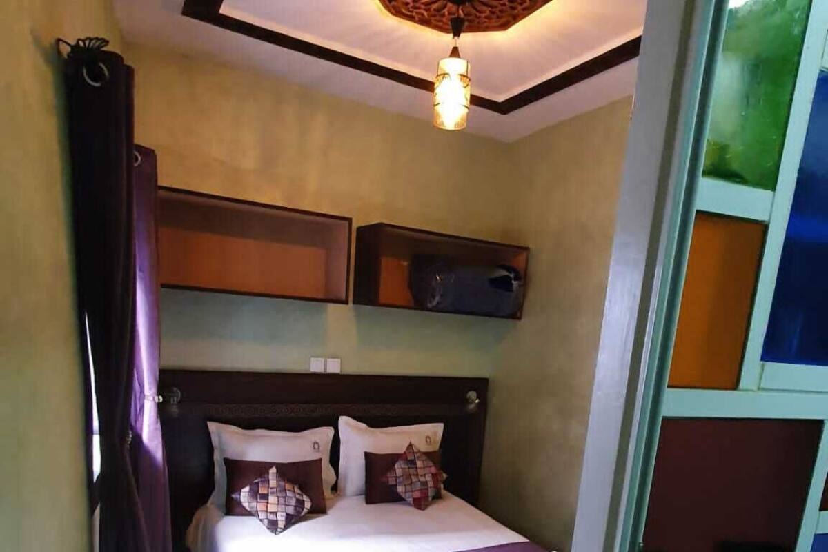 Habitación de hotel con cama, lámpara de techo y ventana con vistas.