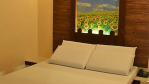 A neatly made bed with white linens and pillows, a folded towel on the bed, and a wooden headboard. - Astrotel Anonas (Quezon City)