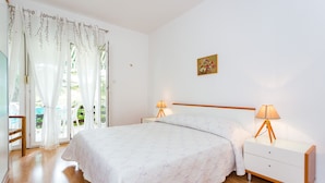 A bedroom with a bed, bedside tables, a lamp, a picture on the wall, and a window with curtains.