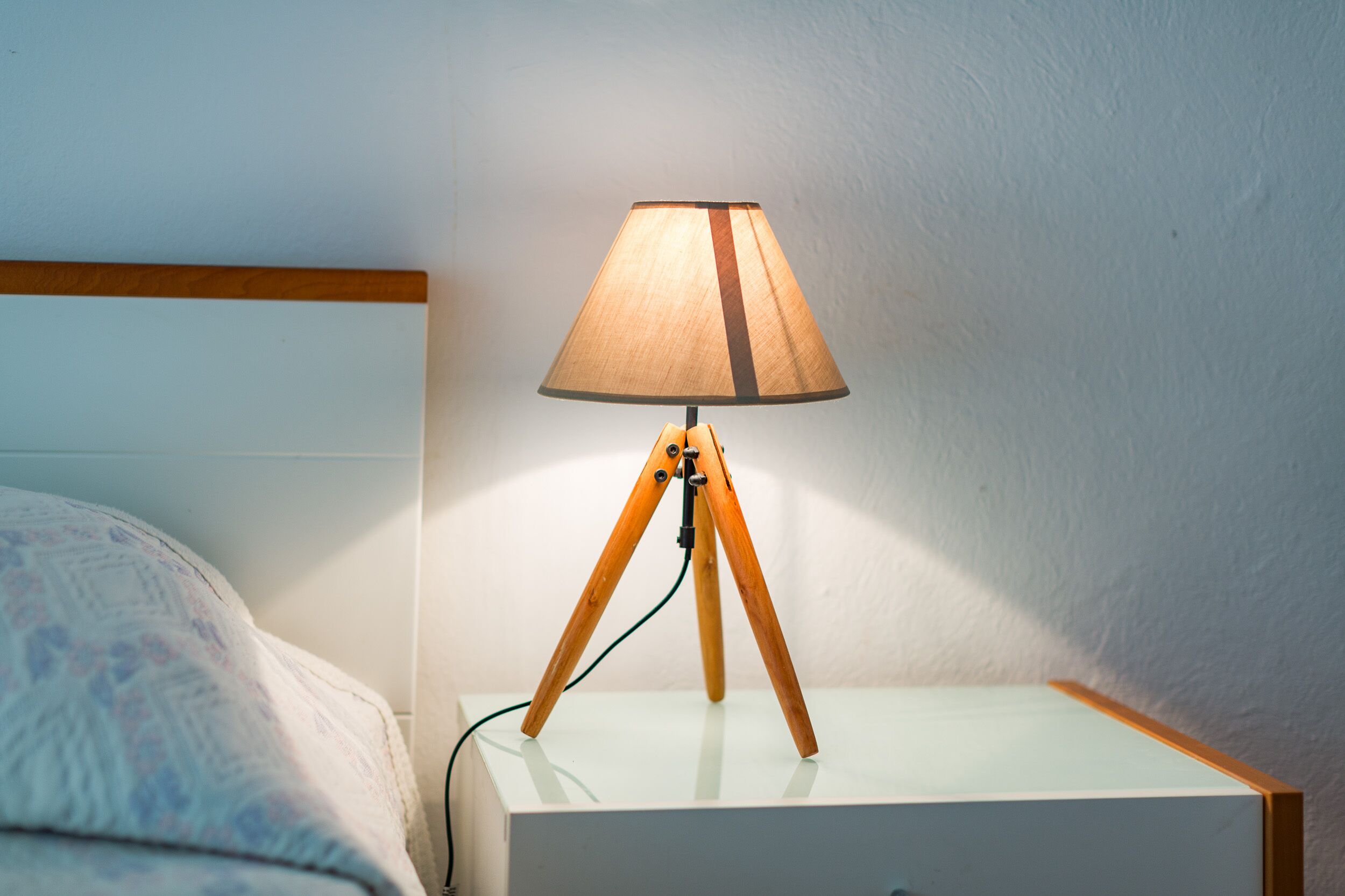 Un comodino con una lampada su un piccolo tavolo da notte bianco.