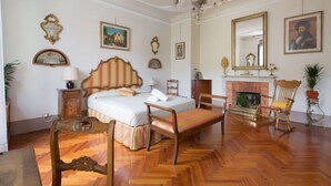 Ein Schlafzimmer mit einem Bett, Holzstühlen, einem Kamin und Wandbildern.