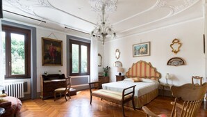 Ein Schlafzimmer mit einem Bett, einem Schreibtisch, einem Stuhl, einer Deckenleuchte und einem Fenster.