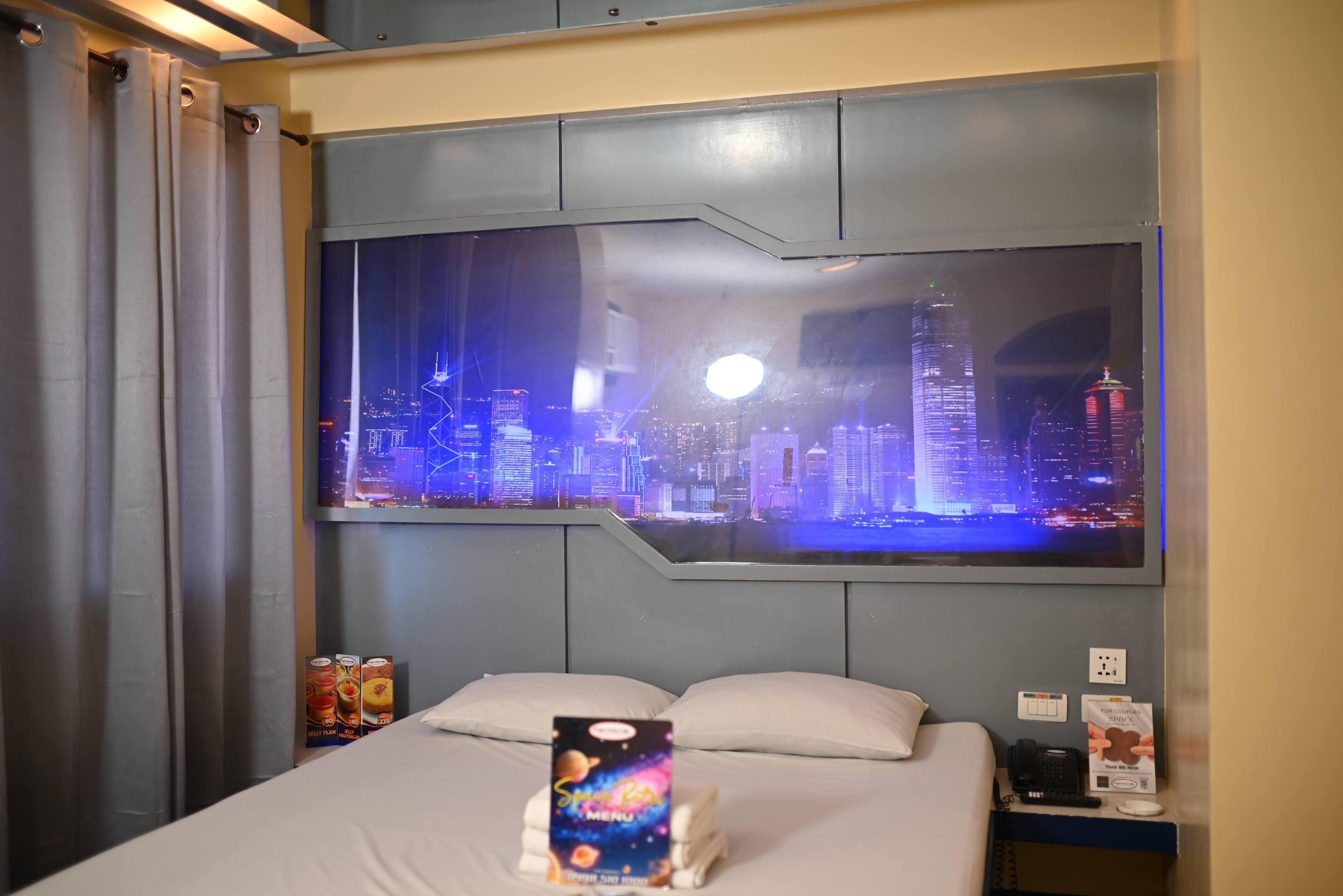Una habitación de hotel con un ventanal grande que muestra un paisaje urbano nocturno.
