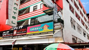 A multi-story building with a red and white facade, featuring a large sign for 'Astrotel' and 'Chubby's Cafe' on the ground floor. - Astrotel Guadalupe (Makati)