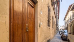 A narrow street with a wooden door, stone pavement, and parked cars.